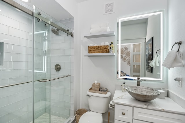 bathroom featuring a shower with door, vanity, and toilet