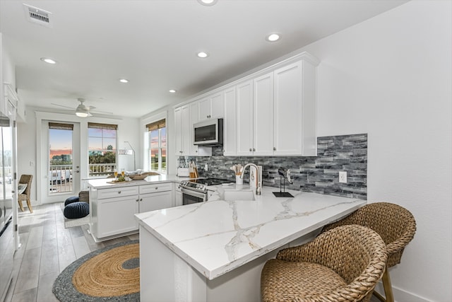 kitchen featuring kitchen peninsula, white cabinetry, stainless steel appliances, and sink