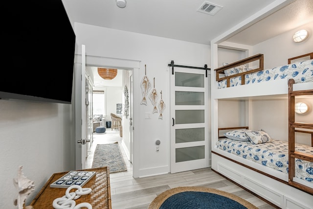 bedroom with light hardwood / wood-style floors and a barn door