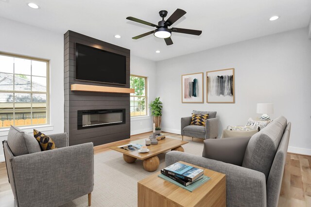 living room with ceiling fan, a fireplace, and light hardwood / wood-style flooring