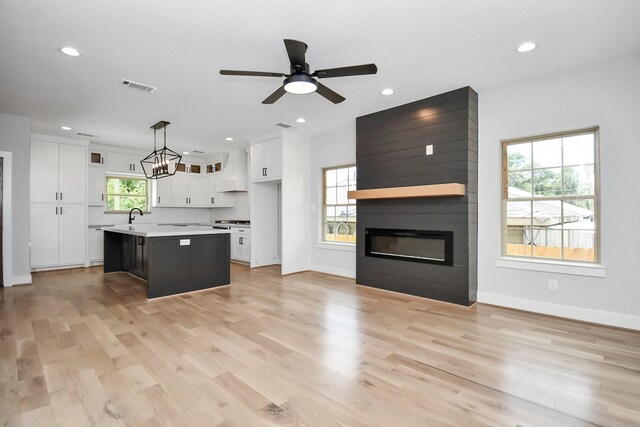 kitchen with white cabinetry, a center island, light hardwood / wood-style floors, and hanging light fixtures