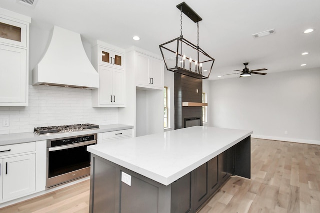 kitchen with white cabinetry, premium range hood, a center island, and appliances with stainless steel finishes