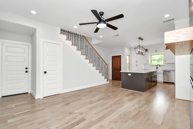 kitchen with light hardwood / wood-style flooring, dishwasher, white cabinetry, hanging light fixtures, and a kitchen island