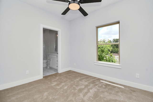 unfurnished bedroom featuring ceiling fan, ensuite bath, and light carpet