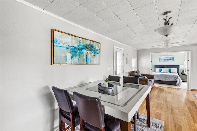 dining space with ceiling fan, crown molding, and wood finished floors