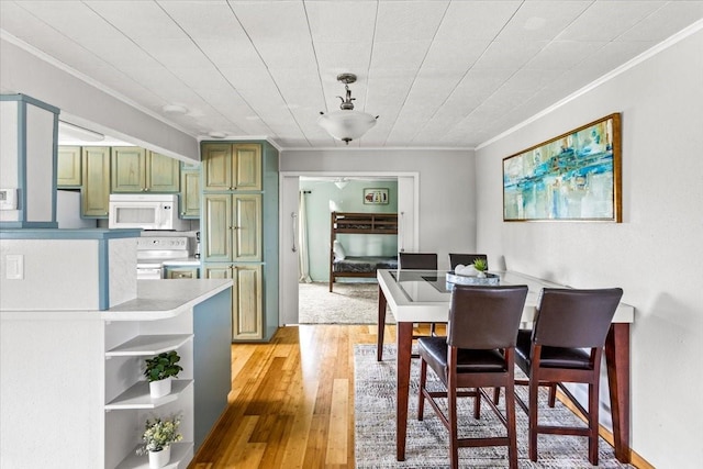 dining area featuring light wood-type flooring and crown molding