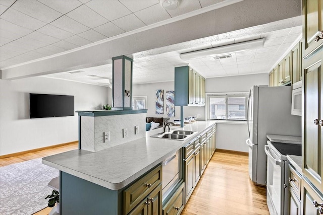 kitchen featuring a peninsula, white appliances, a sink, open floor plan, and crown molding