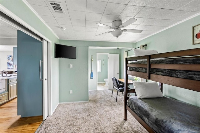 bedroom featuring light colored carpet, a sink, visible vents, baseboards, and ornamental molding