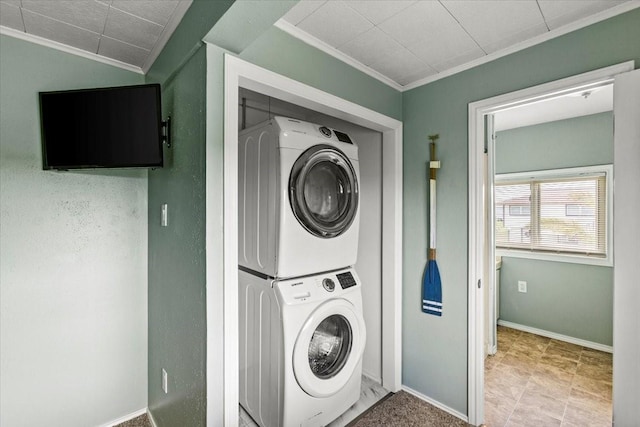 laundry area featuring laundry area, crown molding, baseboards, and stacked washer / drying machine