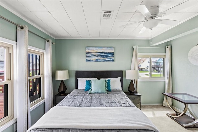 bedroom with carpet floors, visible vents, ornamental molding, a ceiling fan, and baseboards