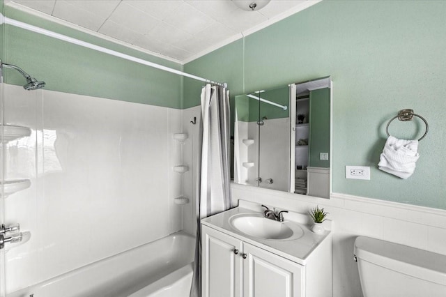 bathroom with toilet, vanity, wainscoting, shower / bath combo, and crown molding