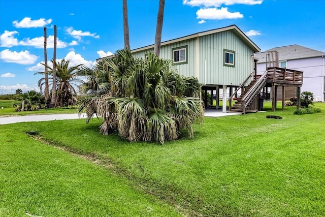 back of property with a carport, stairway, and a lawn