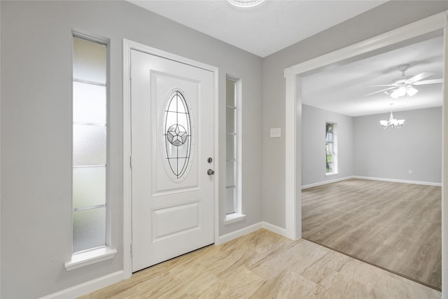 entrance foyer with ceiling fan with notable chandelier and light wood-type flooring