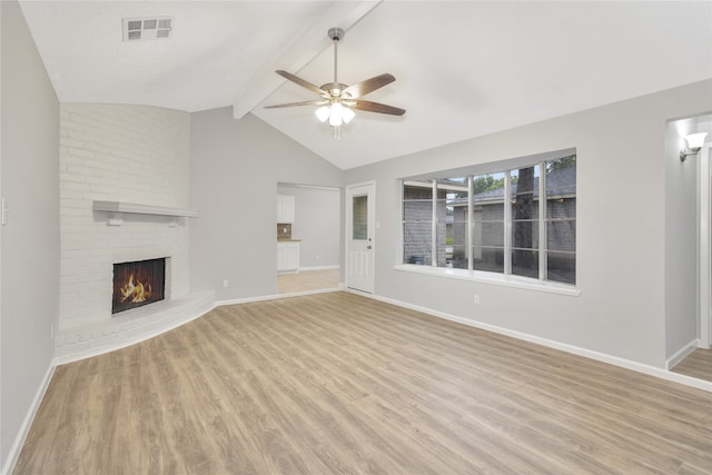 unfurnished living room featuring vaulted ceiling with beams, light hardwood / wood-style floors, a brick fireplace, brick wall, and ceiling fan