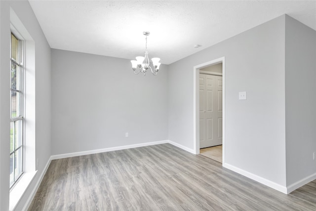 spare room with hardwood / wood-style flooring and a notable chandelier