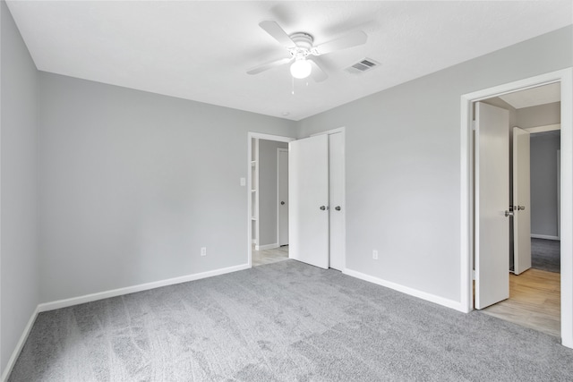 unfurnished bedroom featuring a closet, light colored carpet, and ceiling fan