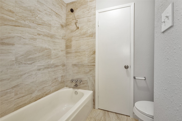 bathroom featuring tiled shower / bath combo and toilet