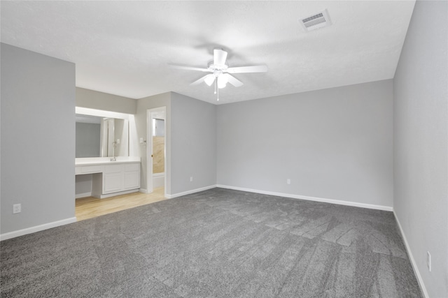 unfurnished bedroom featuring light carpet, ensuite bath, and ceiling fan