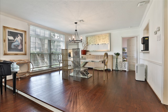 dining space featuring a textured ceiling, ornamental molding, dark wood-type flooring, and a chandelier