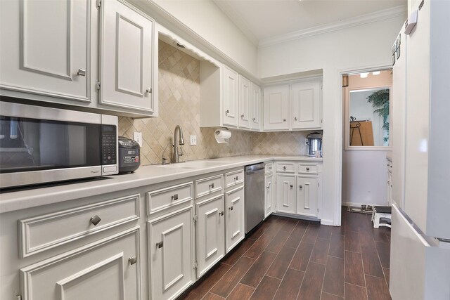 kitchen featuring appliances with stainless steel finishes, ornamental molding, sink, white cabinets, and dark hardwood / wood-style floors