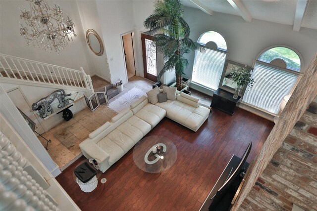 living room featuring beam ceiling, a high ceiling, and wood-type flooring