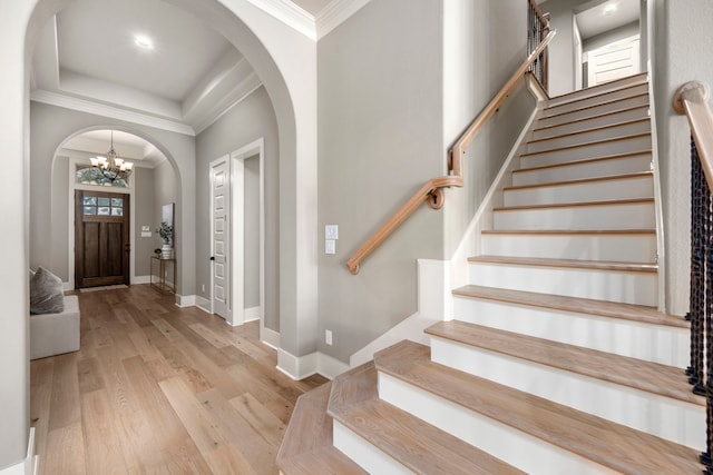 foyer with an inviting chandelier, ornamental molding, and light hardwood / wood-style floors