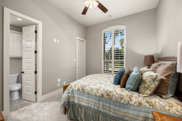 bedroom featuring light colored carpet, ceiling fan, and ensuite bathroom