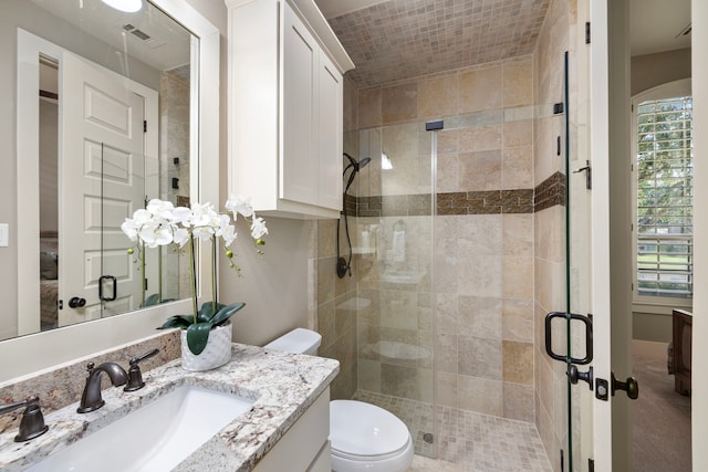 bathroom with a shower with door, vanity, and toilet