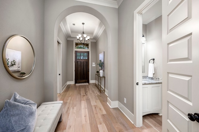 entryway featuring ornamental molding, a notable chandelier, and light hardwood / wood-style floors