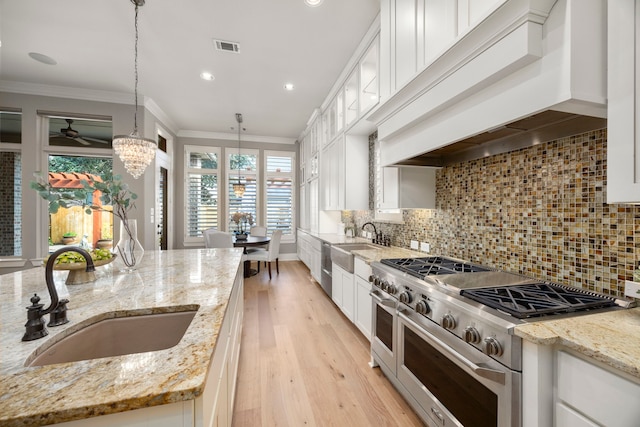 kitchen with range with two ovens, light stone countertops, sink, and decorative light fixtures