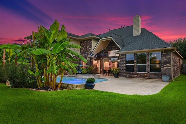 back house at dusk with a patio and a yard