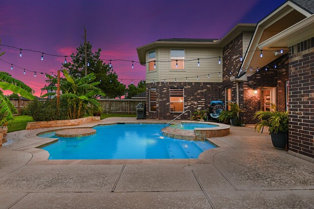 pool at dusk with a patio area and an in ground hot tub