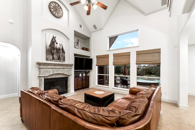 living room featuring a high end fireplace, high vaulted ceiling, light tile patterned flooring, and ceiling fan