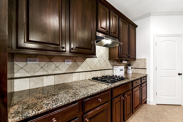 kitchen with dark stone counters, tasteful backsplash, stainless steel gas stovetop, light tile patterned flooring, and ornamental molding