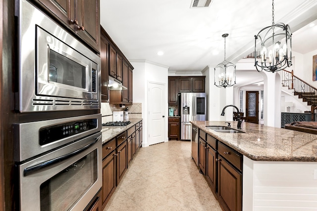 kitchen featuring tasteful backsplash, an inviting chandelier, appliances with stainless steel finishes, pendant lighting, and sink