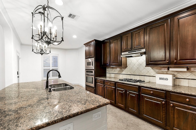 kitchen featuring stainless steel appliances, hanging light fixtures, sink, and an inviting chandelier