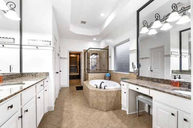 bathroom with vanity, tile patterned flooring, a tray ceiling, and tiled bath