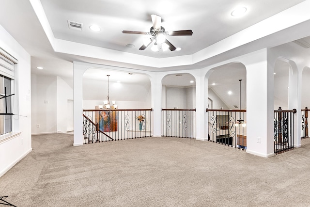 spare room with a tray ceiling, light carpet, and ceiling fan with notable chandelier