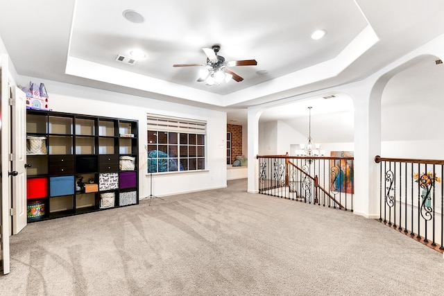 interior space featuring ceiling fan with notable chandelier, a raised ceiling, and carpet floors