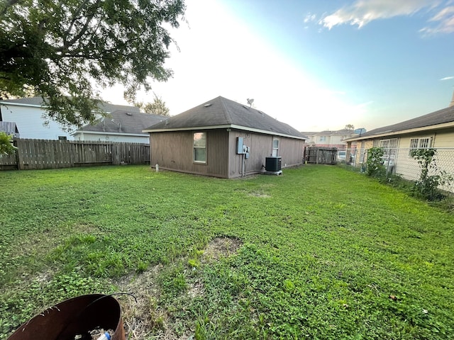 rear view of house featuring central AC unit and a lawn