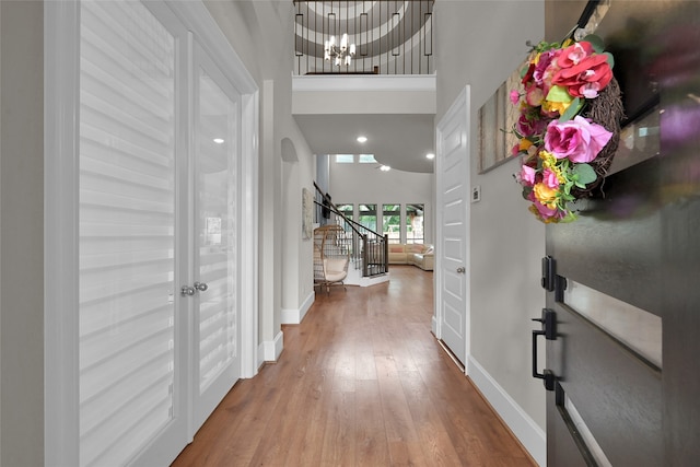 foyer entrance with a chandelier, hardwood / wood-style floors, and a towering ceiling