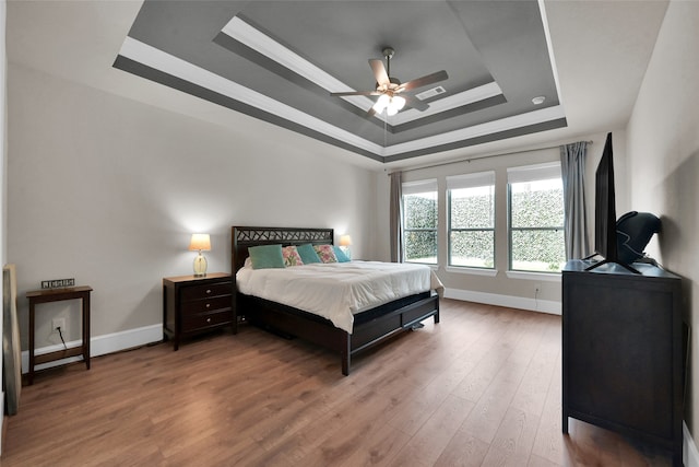 bedroom featuring a raised ceiling, hardwood / wood-style floors, and ceiling fan