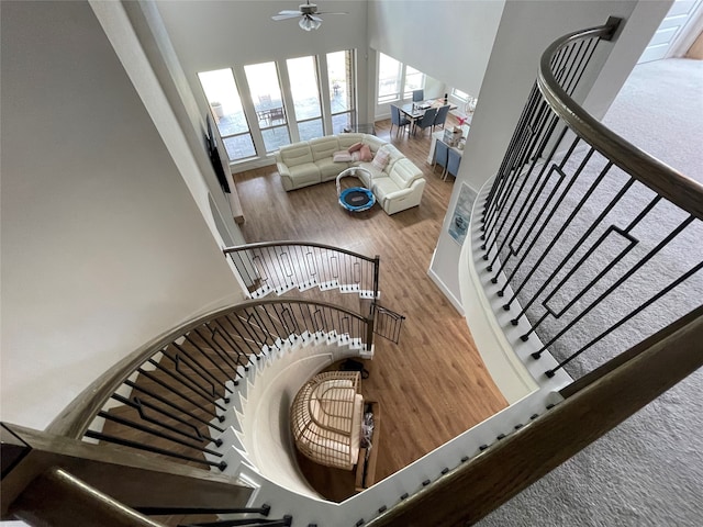 stairway featuring hardwood / wood-style flooring, a towering ceiling, and ceiling fan