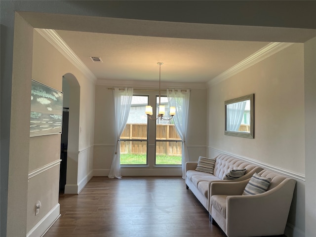 sitting room with dark wood-type flooring, a notable chandelier, and ornamental molding