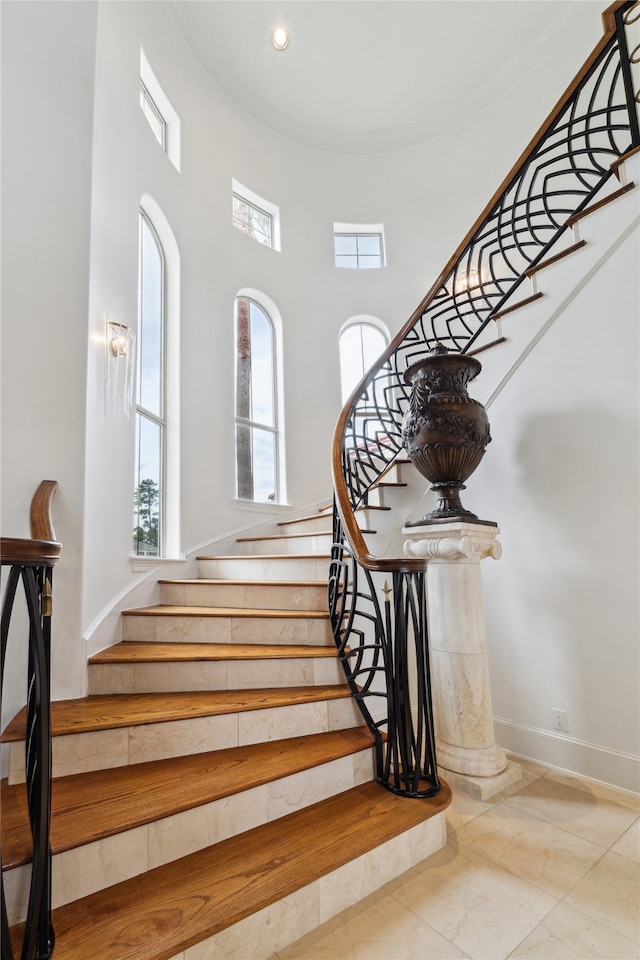 stairs featuring ornamental molding, tile patterned floors, and a towering ceiling