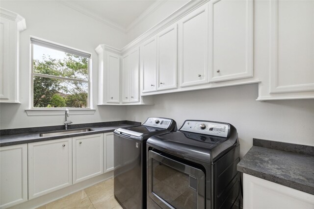 laundry room featuring washing machine and clothes dryer, sink, cabinets, light tile patterned floors, and crown molding