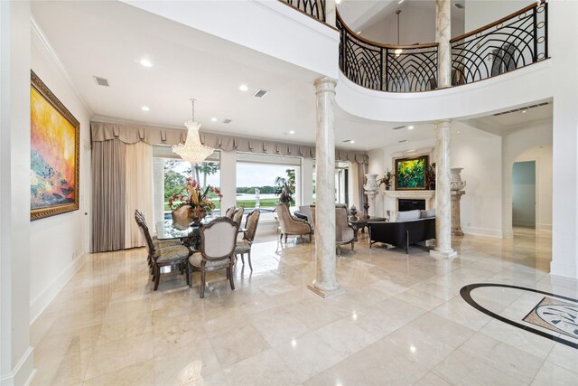 tiled dining room with decorative columns, crown molding, and a high ceiling