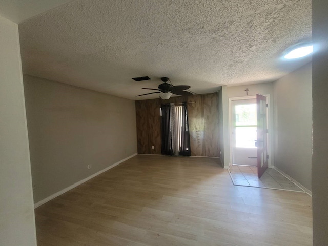 empty room featuring ceiling fan, light wood-type flooring, and a textured ceiling