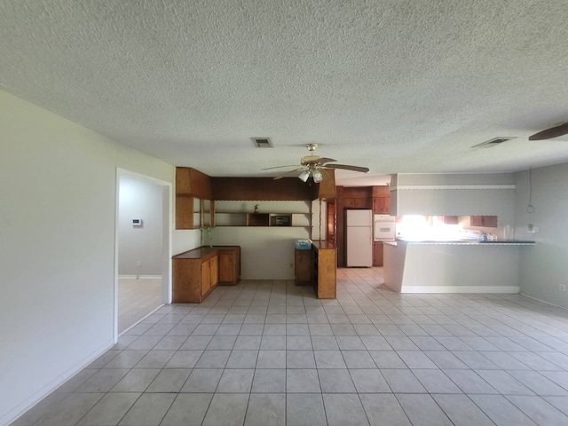 kitchen with a textured ceiling, light tile patterned floors, kitchen peninsula, ceiling fan, and white refrigerator