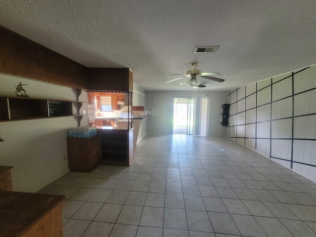 kitchen featuring ceiling fan, kitchen peninsula, a textured ceiling, and light tile patterned floors